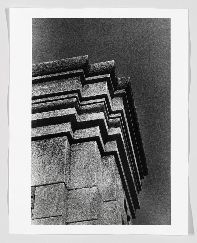 Stepped concrete building corner with layered geometric ledges against a dark sky.