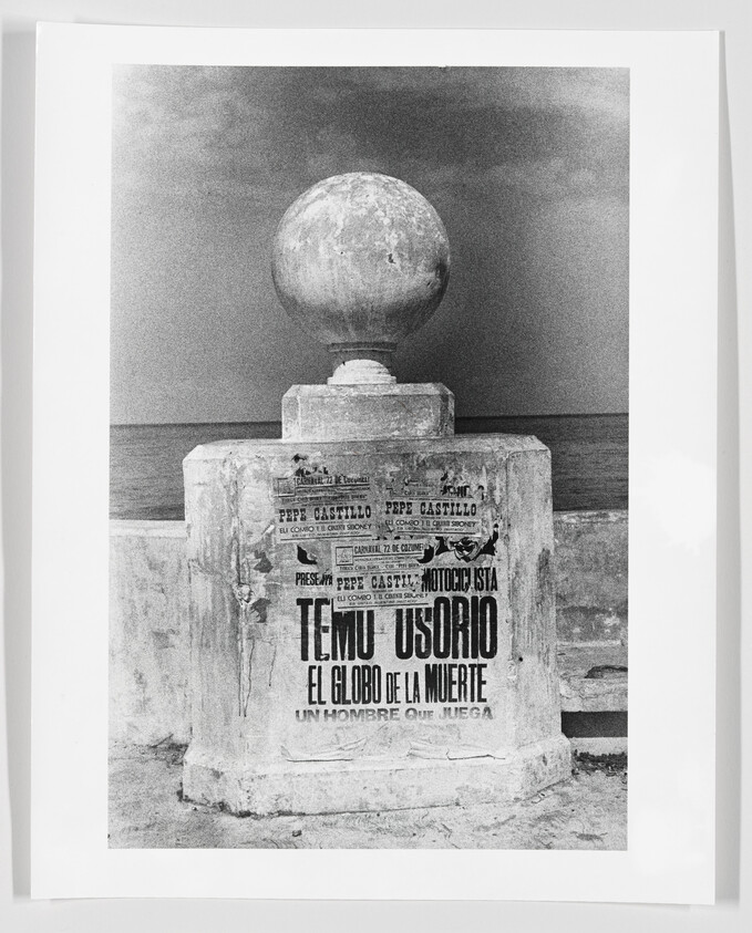 Stone seawall pedestal topped by a large sphere with a poster reading "El Globo de la Muerte."