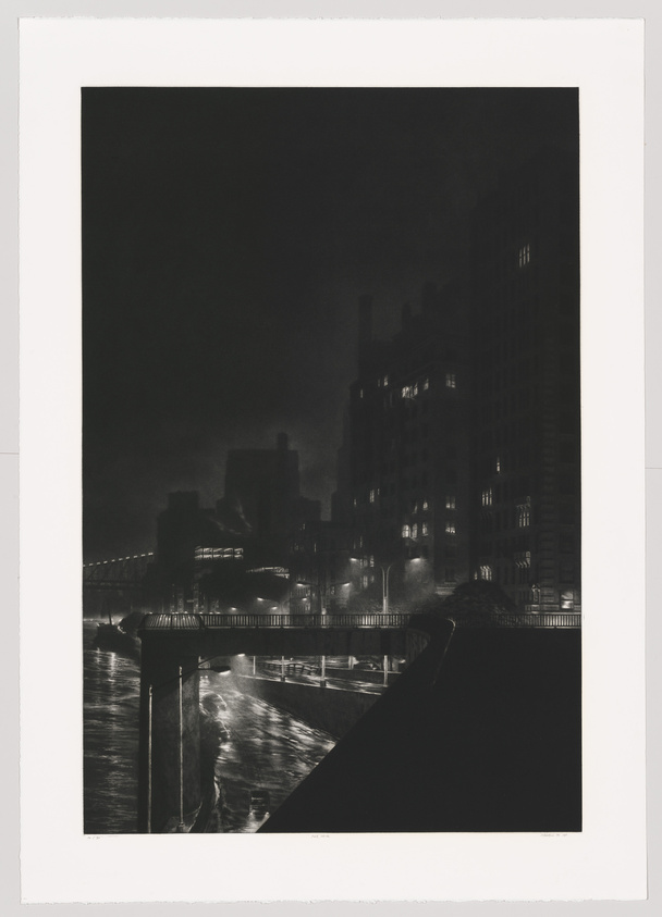 A black and white photograph depicting a nighttime cityscape with illuminated buildings and a bridge. The light reflects off a body of water in the foreground, creating a contrast with the dark sky and surrounding shadows.