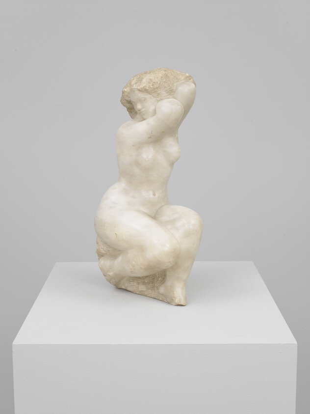 A marble sculpture of a seated nude woman raising her arms behind her head on a pedestal.