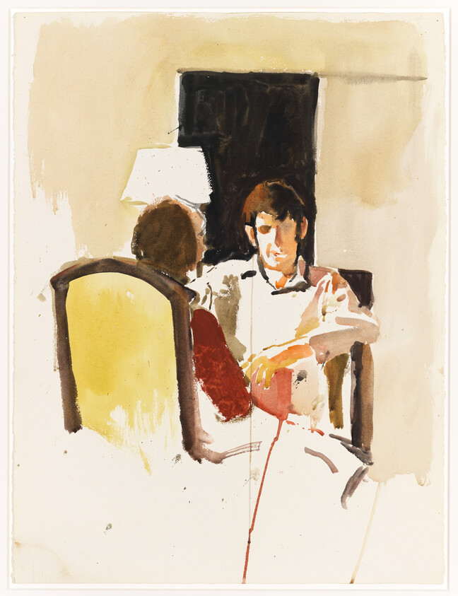 Two people sit facing each other in armchairs as one person speaks by a lamp.