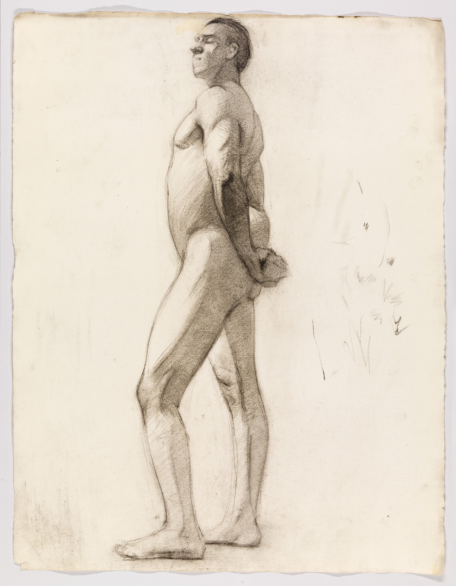 A standing nude man in profile with hands clasped behind his back.
