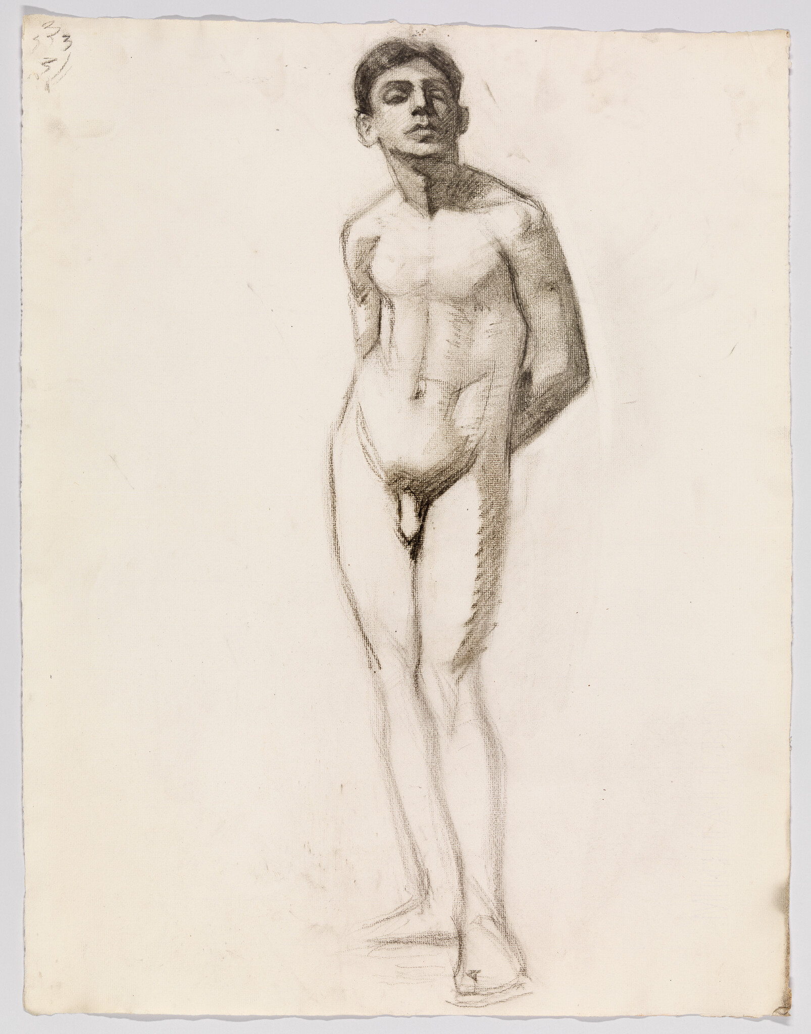 Young nude man standing with hands behind his back, looking upward and slightly to the side.