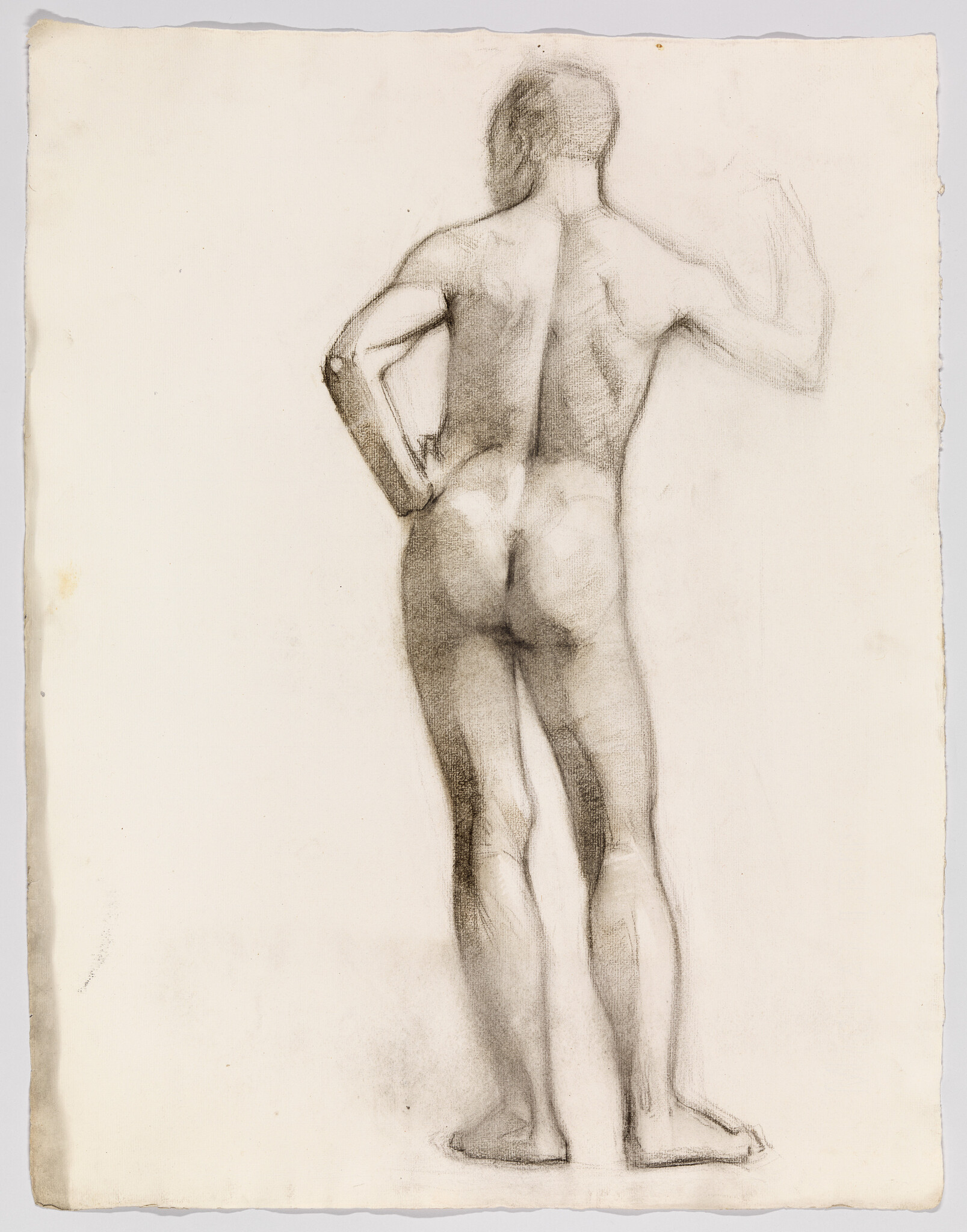 A standing nude man seen from the back with one hand on his hip and the other raised.