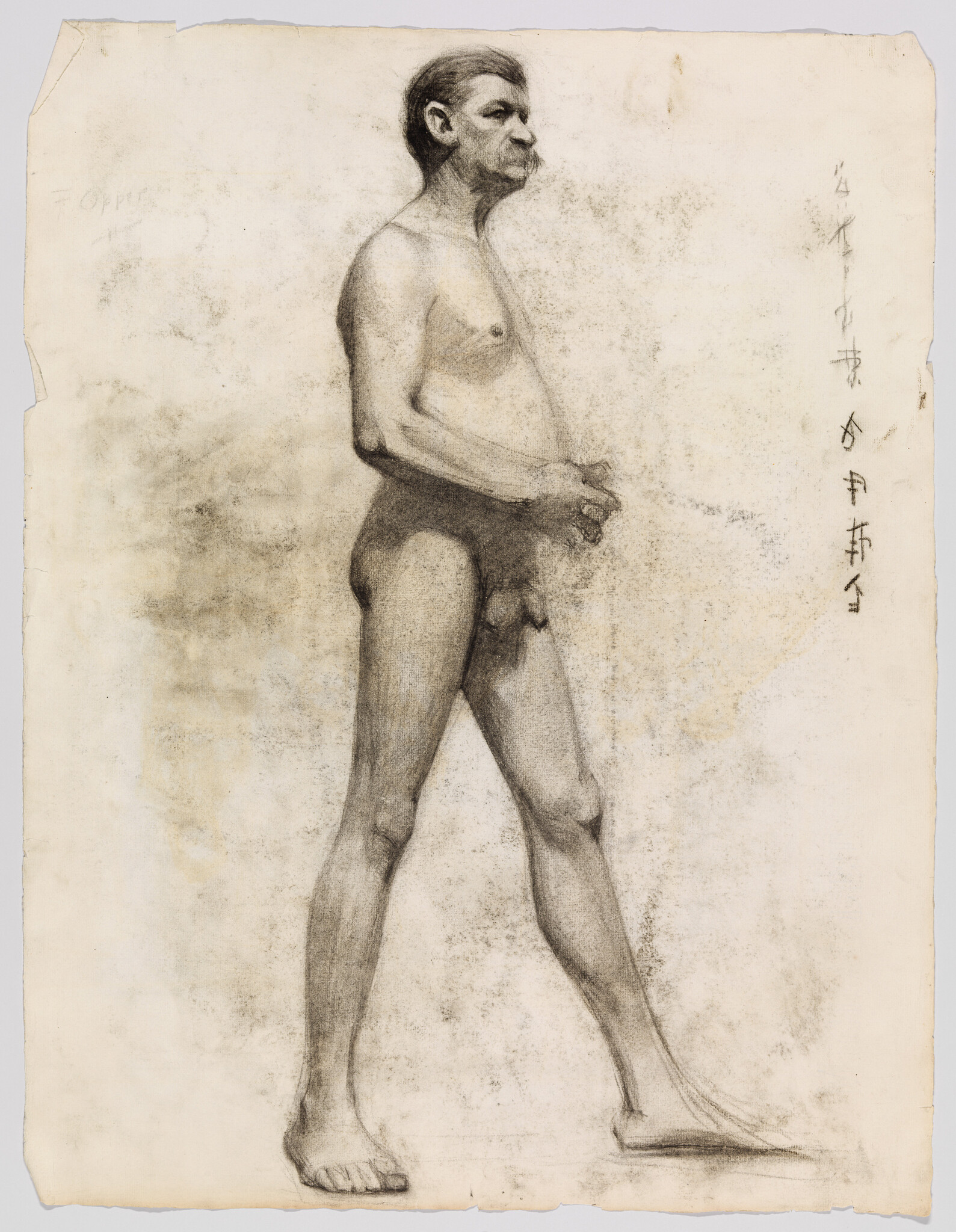 A standing nude man in profile with hands clasped, looking forward.