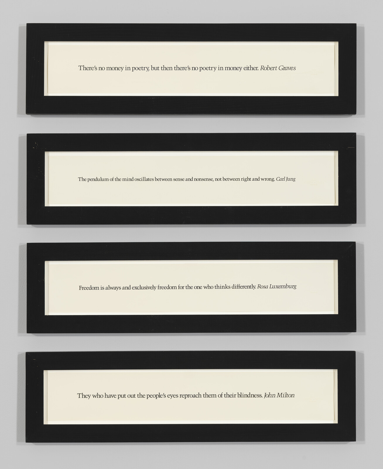 Four narrow black-framed panels displaying short printed quotes mounted vertically on a gray wall.