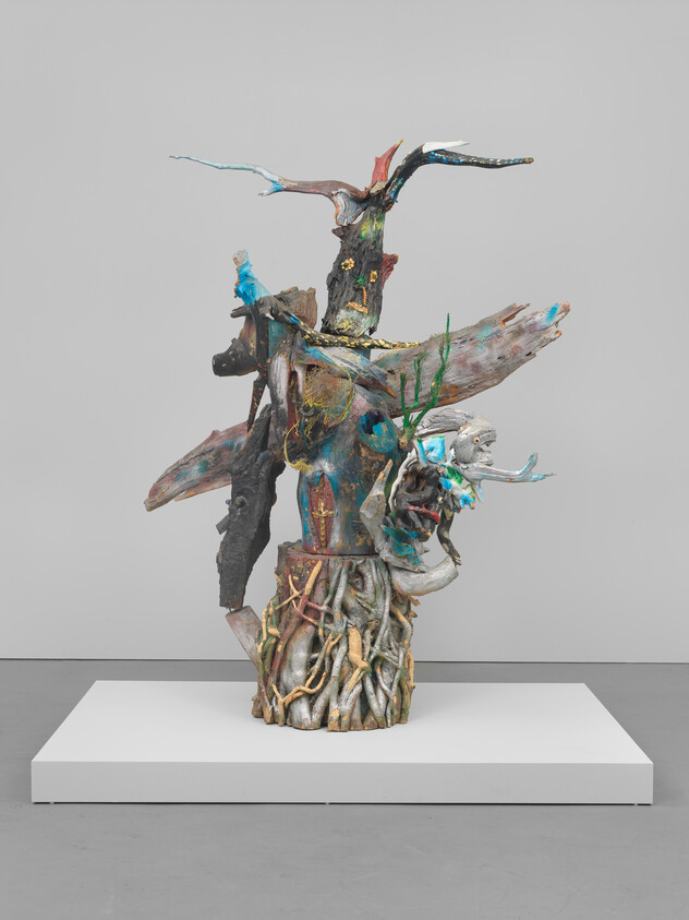 A colorful mixed-media tree-like sculpture with twisted roots and painted branches on a pedestal.