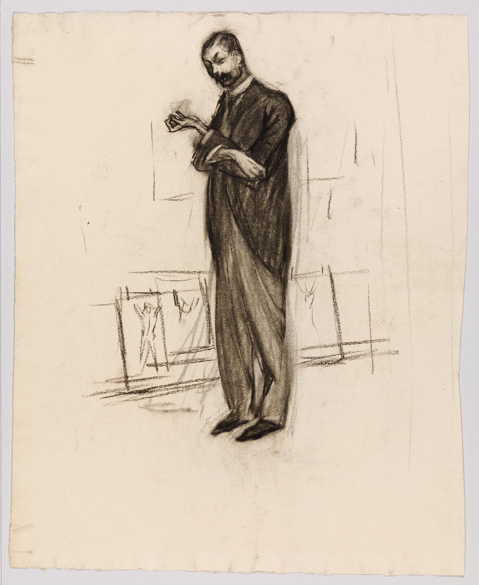 A standing man in a long coat looks down at his hands in thought.