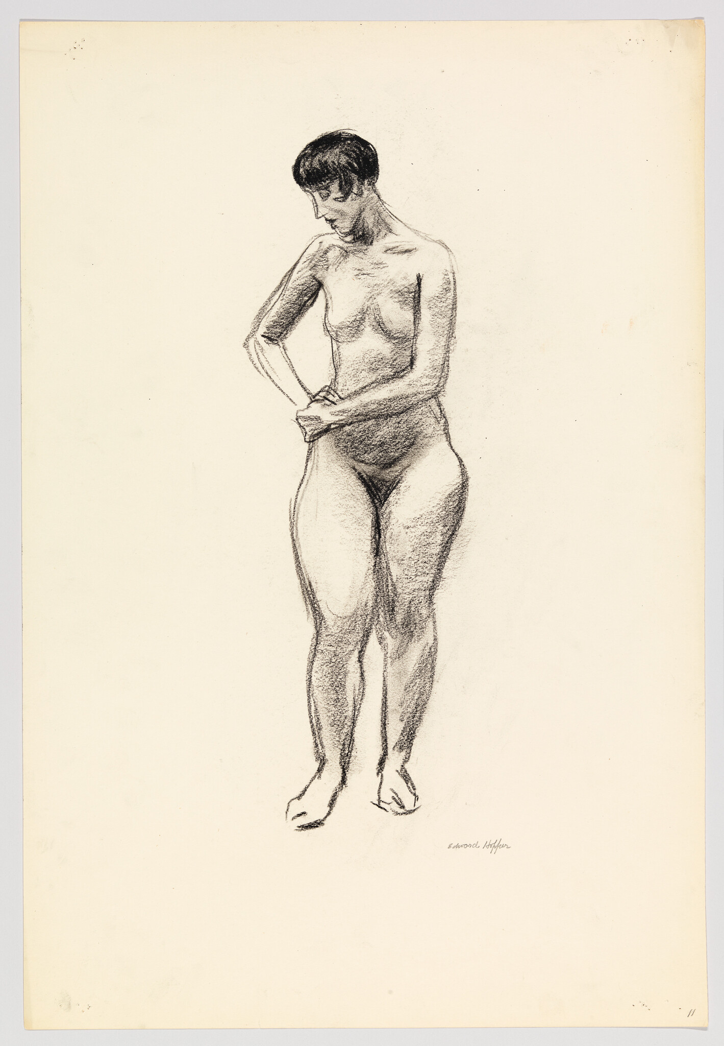 Standing nude woman with short hair looking down and clasping her hands in front.