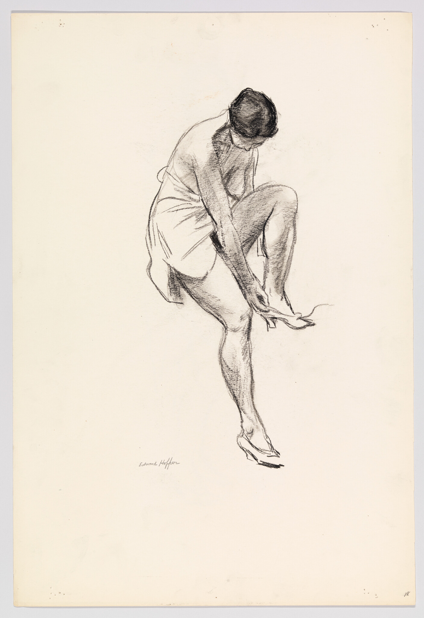 A woman sitting lifts one leg to put on a high-heeled shoe.