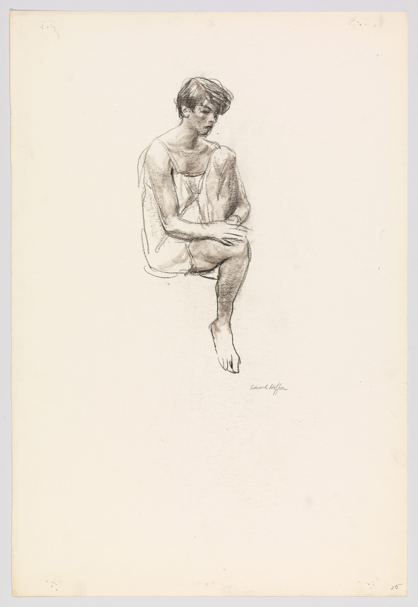 Young person in a loose dress sits with one knee raised, looking downward.