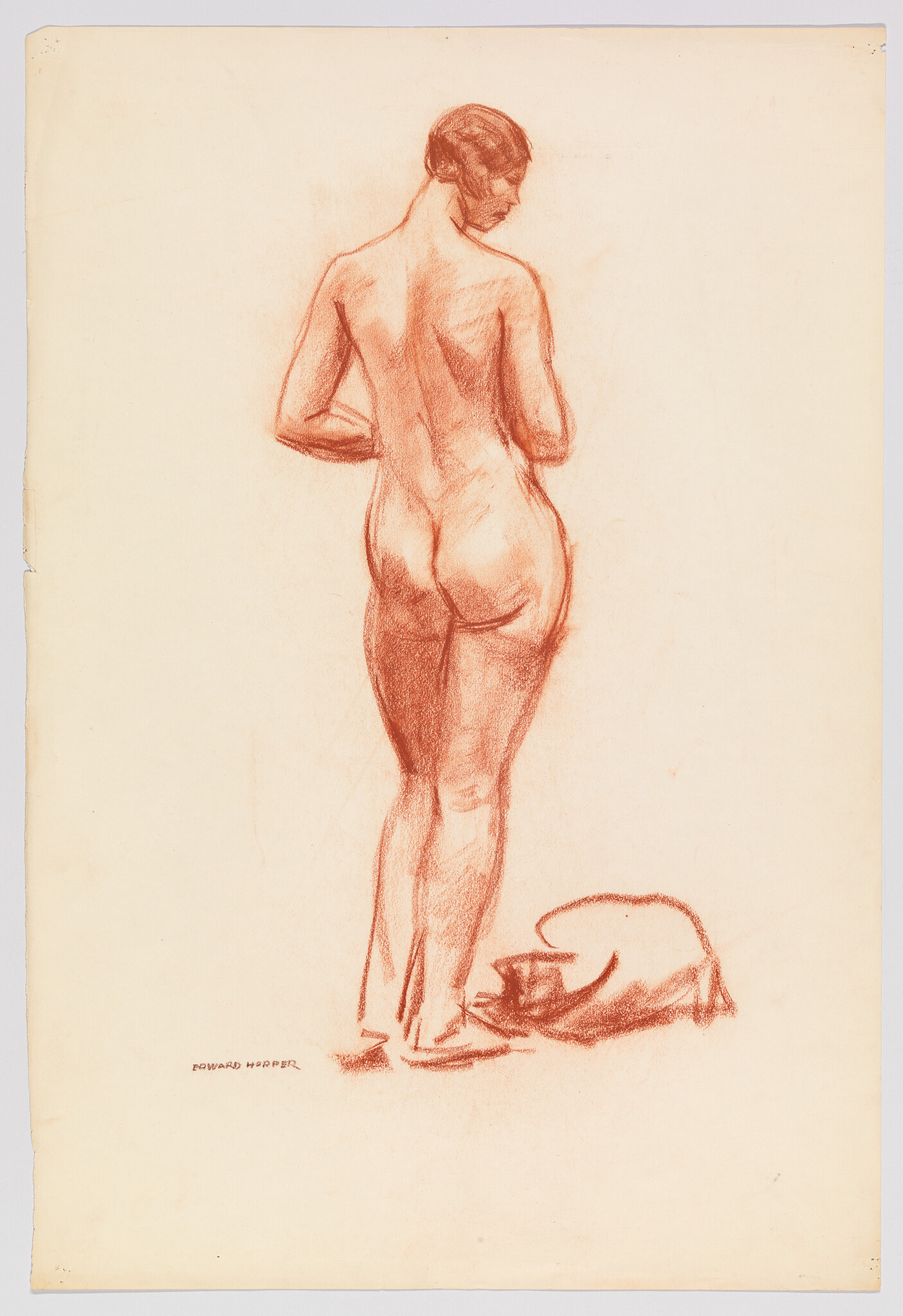 A standing nude woman seen from behind with folded cloth and a bowl on the floor.
