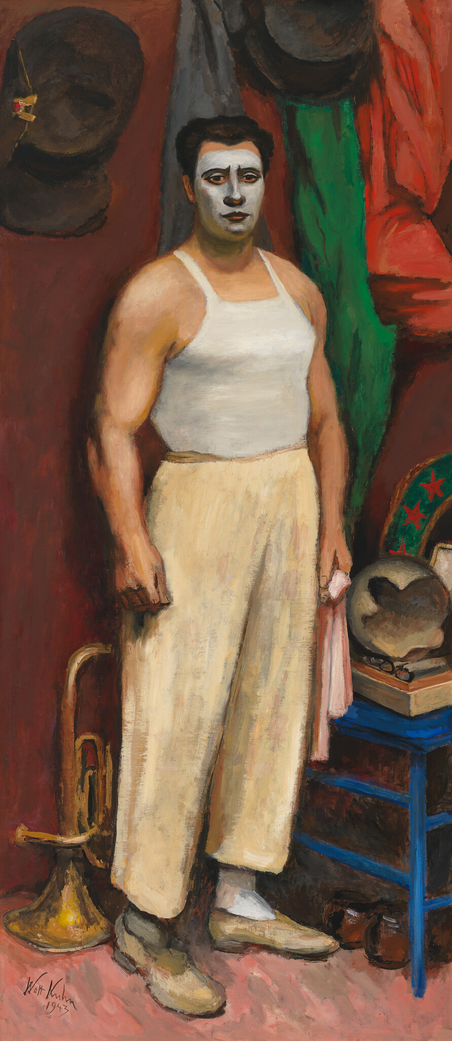 A painting depicting a solemn clown in a white tank top and baggy yellow pants, with white face paint and dark, expressive eyes. The background features a dark hat hanging on the wall, a green and red curtain, and a small table with a boxing glove and other items. The artwork is signed "Walt Kuhn 1938" at the bottom.