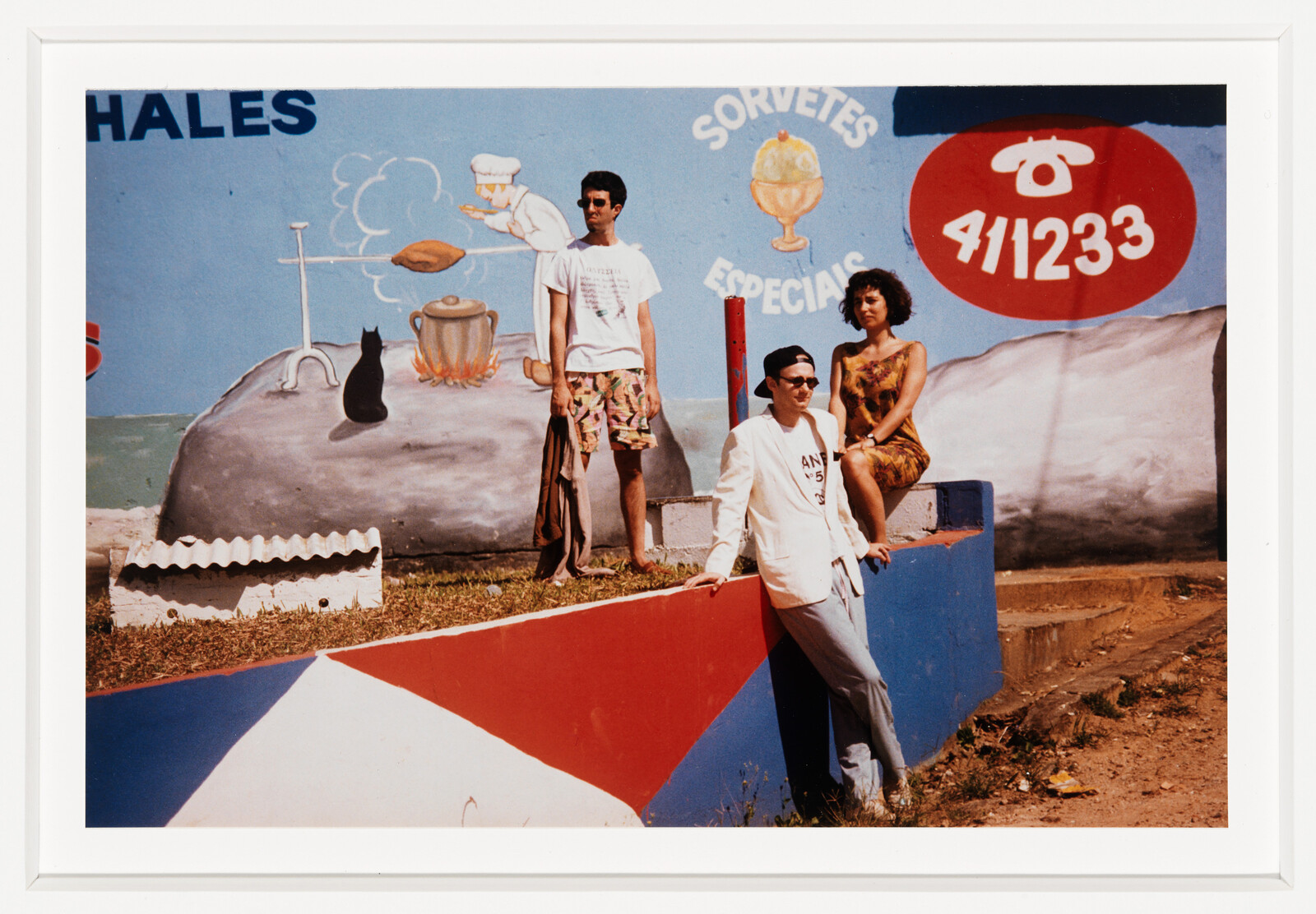 Three friends pose in front of a colorful mural advertising ice cream.