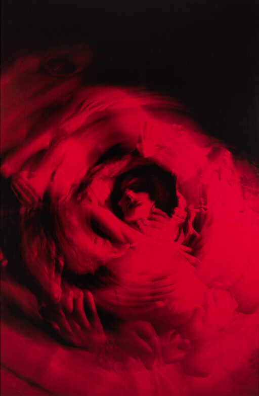 Woman cradled and swirling in red light, blurred motion suggesting movement and embrace.