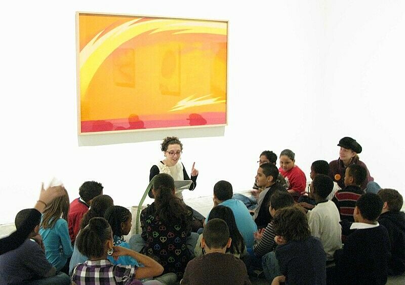 Students talk to a teacher in front of a Georgia O'Keefe painting