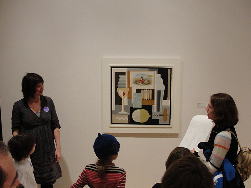 A group of adults and kids stand around a modern painting.