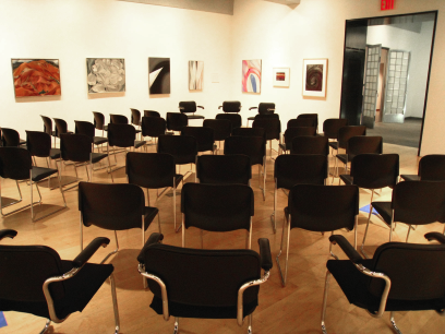 Empty chairs arranged in in concentric circles within a gallery.
