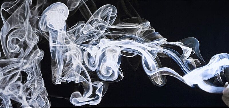 An artwork of white swirls of smoke against a black background.