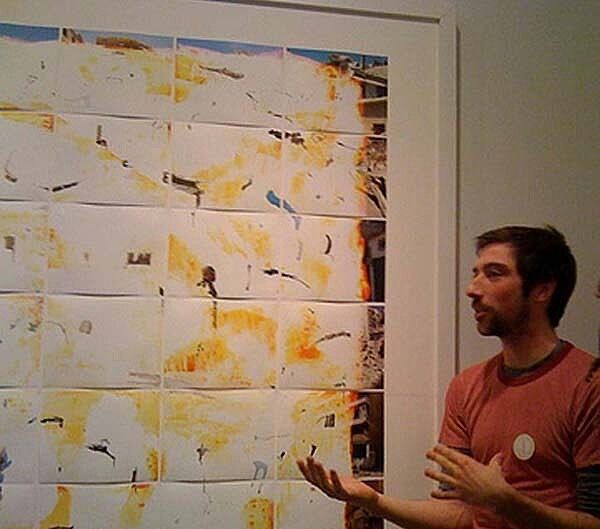 The artist explains his work in front of a photo.