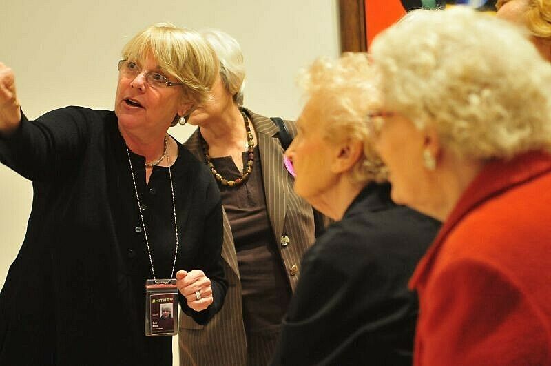 A tour guide talks to senior citizens in the gallery