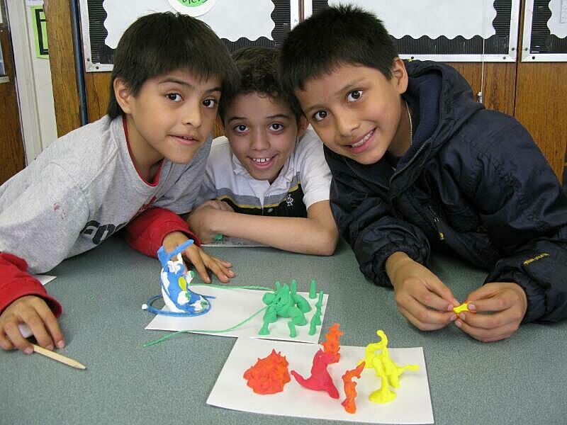 Three children posting with the sculpture models they made