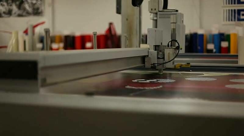A machine cuts holes in a piece of vinyl.