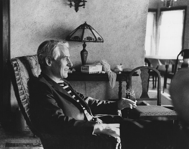 A black and white photo of a man smoking in a chair.