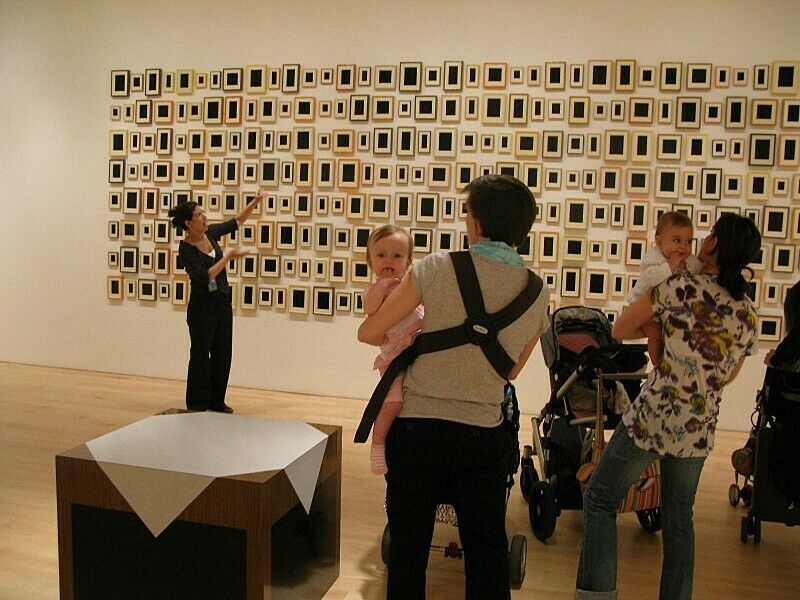 A baby stares at the camera as parents take in Allan McCollum’s 288 Plaster Surrogates.