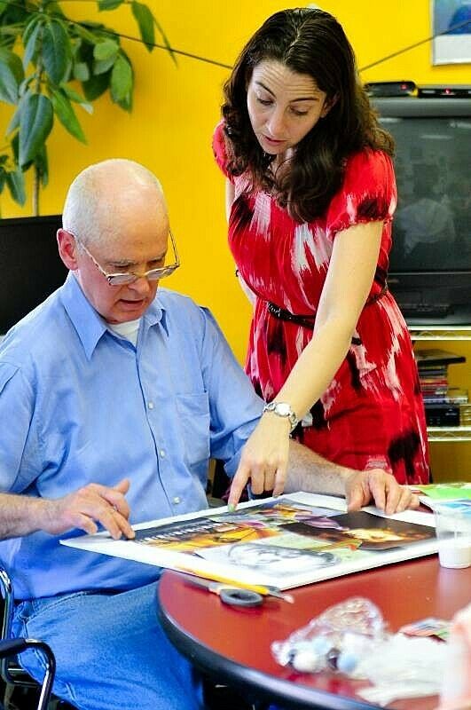 Instructor helping a man with his artwork.