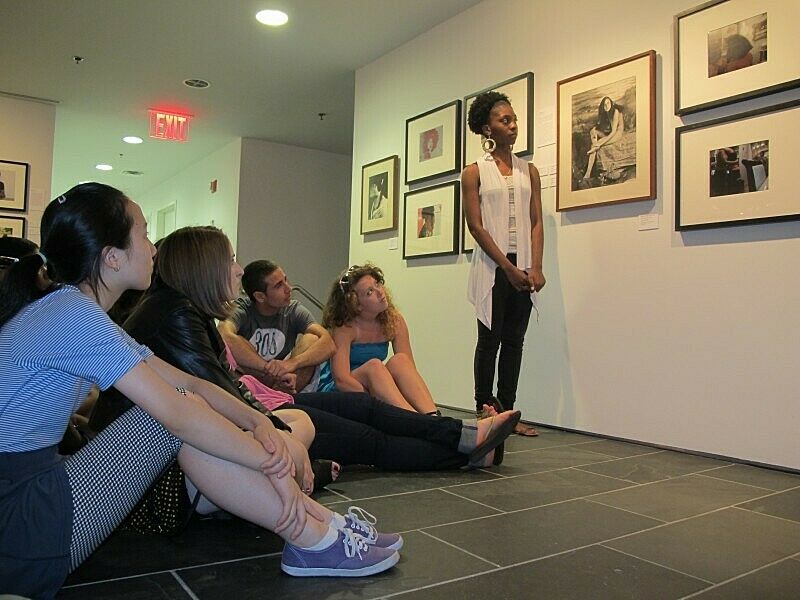 A group of teens listen to an artist talk about her work