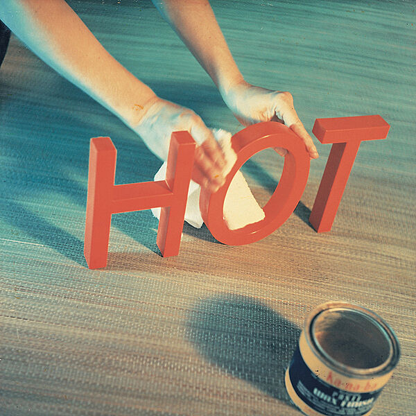 Two hands holding the word "hot" next to a paint can.
