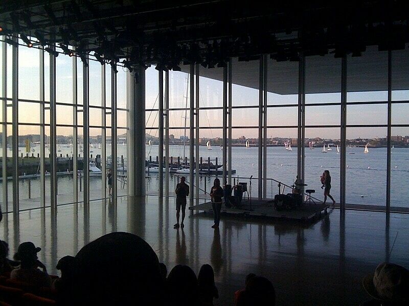 audience and speaker in front of large window with water