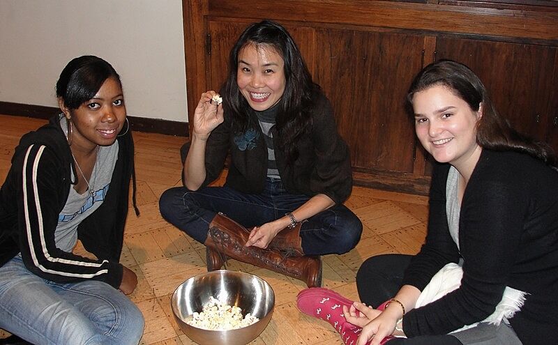three students sitting on floor eating popcorn