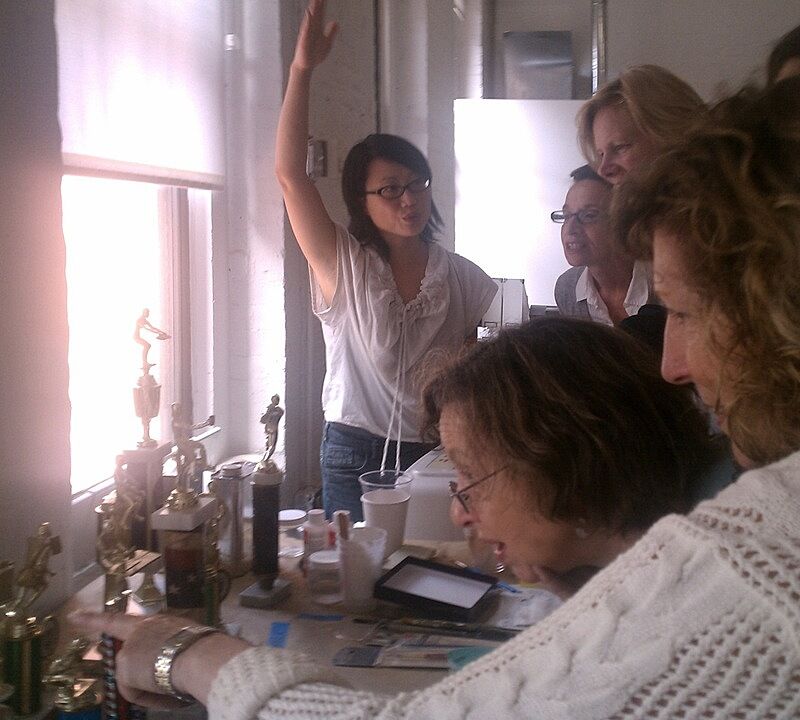 The artist shows participants her collection of sports trophies used for sculpture