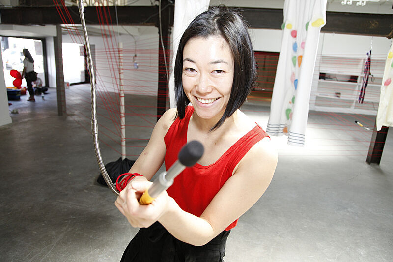 Artist Aki Sasamoto holds a microphone during a community project.