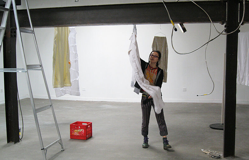 The artist puts up towels on the beams in the installation space.