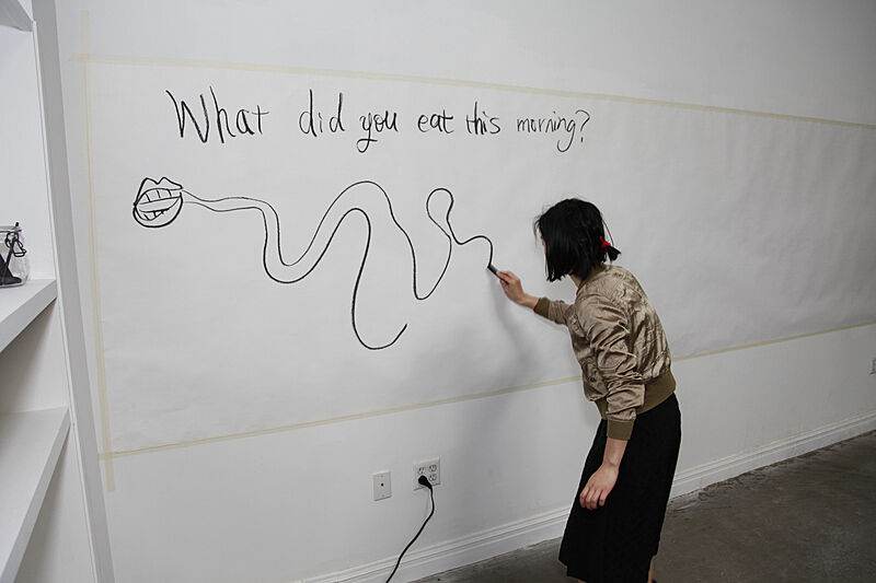 The artist draws lines on a poster wall.