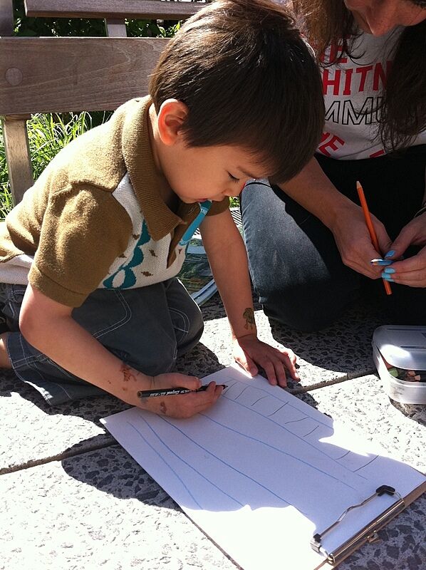 A child draws on paper outside on the High Line.