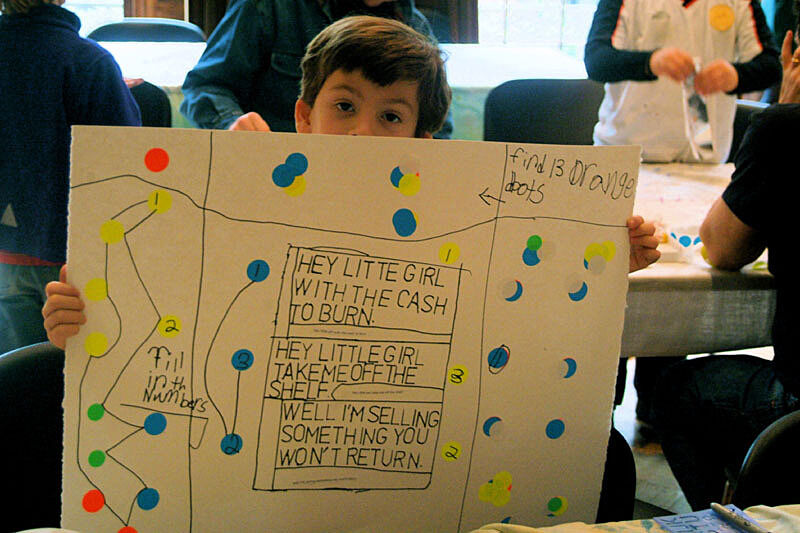 A child holds up their artwork