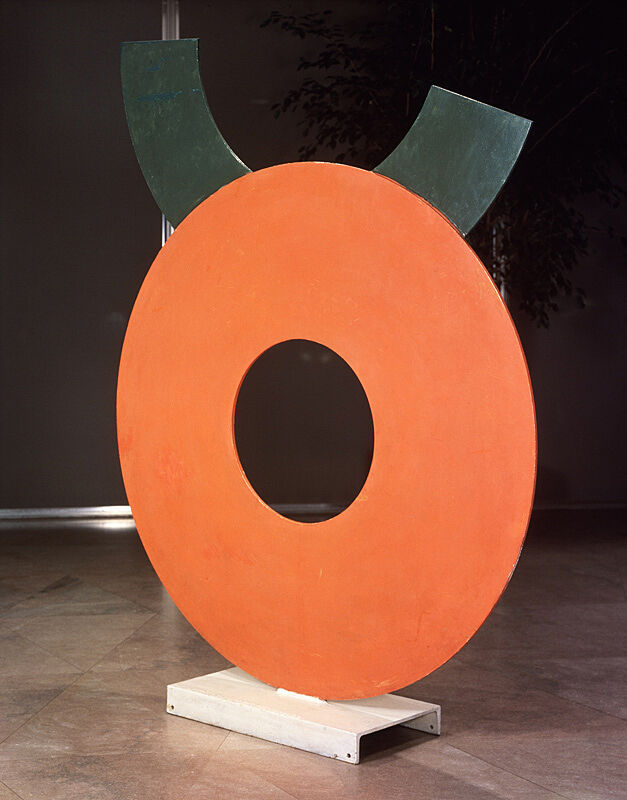 A red circular steel sculpture with a hole in the middle.