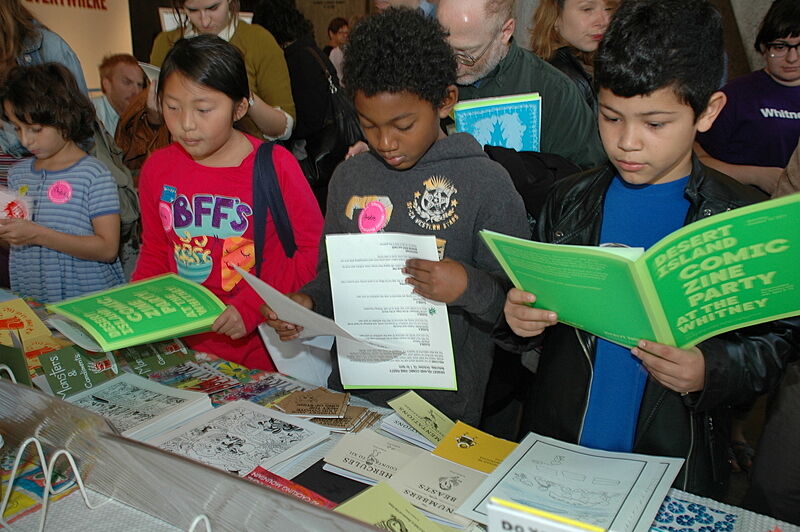 Kids read comic books at a table.