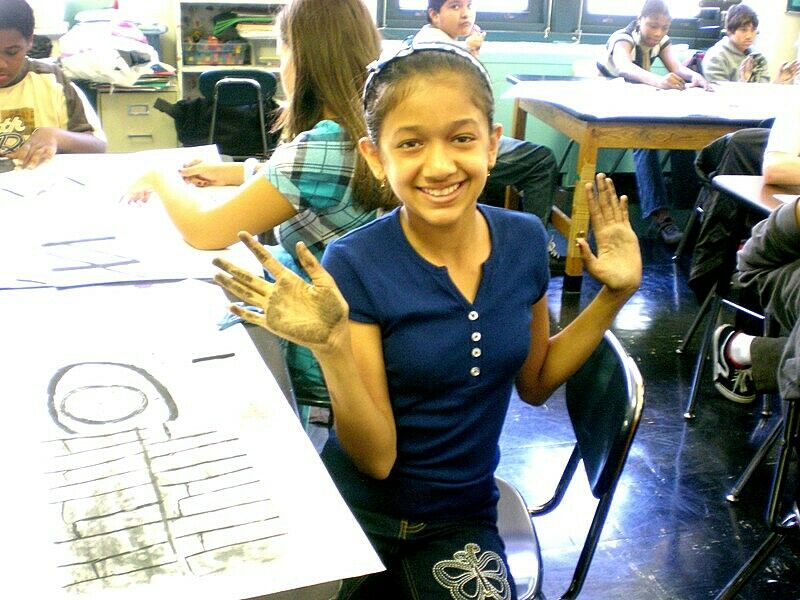 Girl holding up charcoal on her hands.