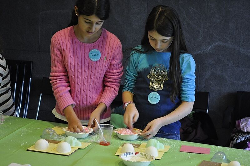 Two students concoct a sugar mixture in paper bowls.