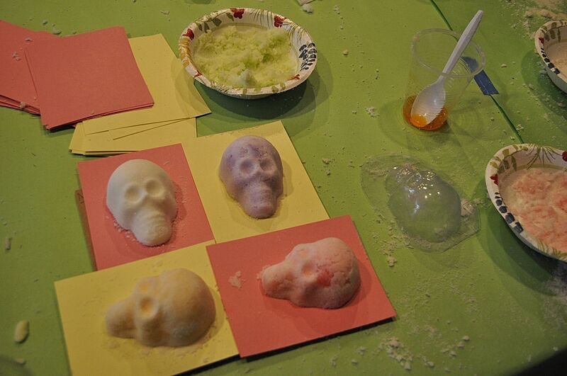 Four sugar skulls lay in colored paper.