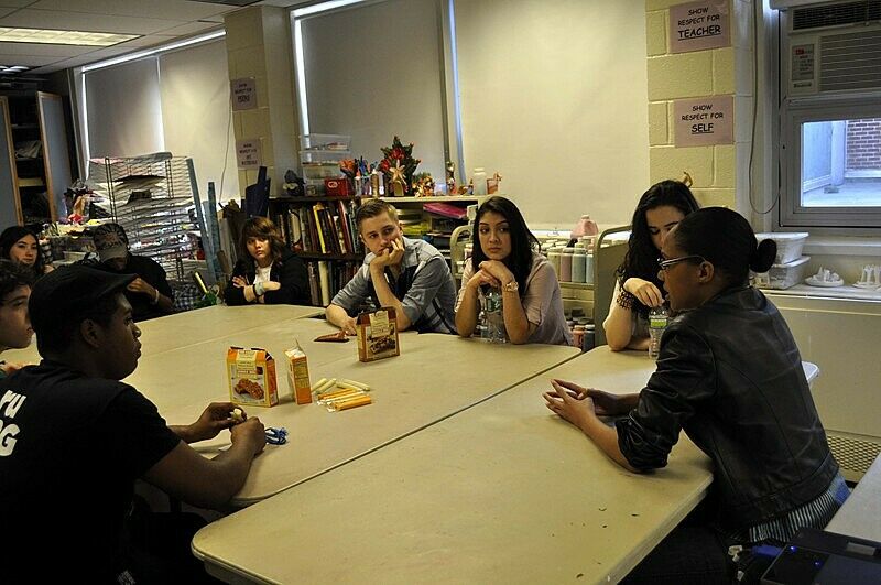 students and artists talk over a table