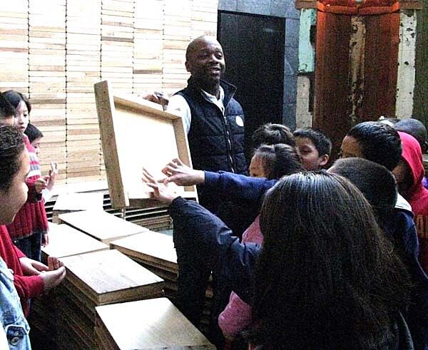artist holding up wood frame for students