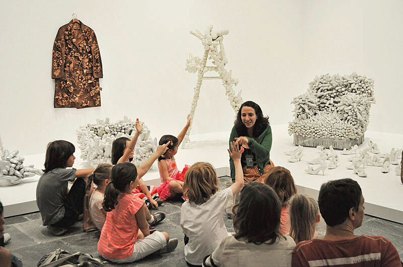 A teacher works with a class in the gallery.
