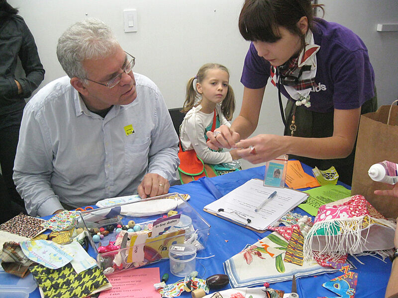 A staff member shows a parent and child how to create art. 