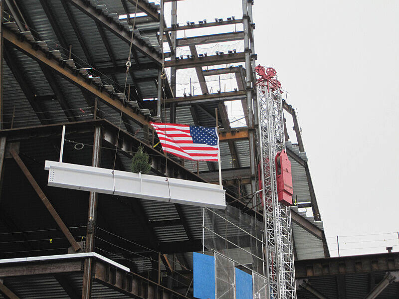 A flag on a beam being raised by a crane